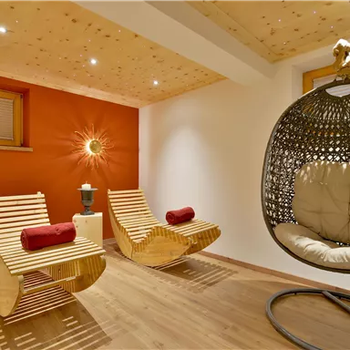 A cozy room with two wooden lounge chairs and a modern shell chair. The walls are in warm colors, and the light creates a relaxed atmosphere.