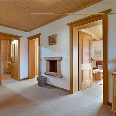 Ein einladender Flur mit Holzvertäfelung und mehreren Türen. Ein Kamin und eine dekorative Kommode sorgen für eine gemütliche Atmosphäre.