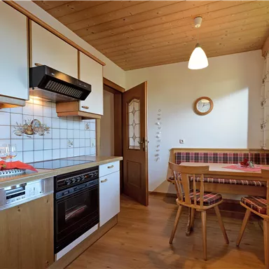 Eine helle und freundliche Küche mit modernen Geräten. Es gibt einen kleinen Essbereich mit Holzstühlen und einer gemütlichen Atmosphäre.
