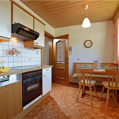 Eine moderne Küche mit Holzregalen und einem Esstisch. Der Raum ist hell erleuchtet und hat eine freundliche Atmosphäre.