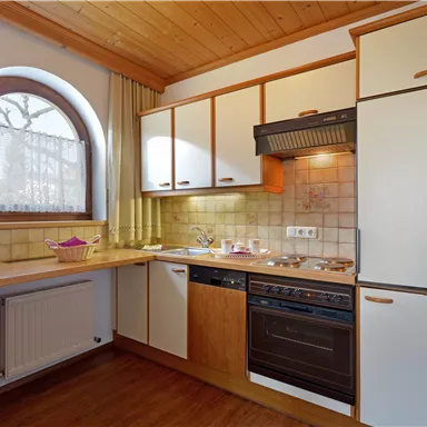 Eine moderne Küche mit Holz- und weißen Schränken. Sie verfügt über einen Herd, eine Spüle und ein großes Fenster.