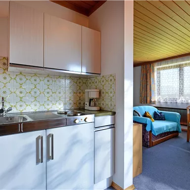 A cozy accommodation with a small kitchen and a living area. Bright colors and plenty of daylight create an inviting atmosphere.
