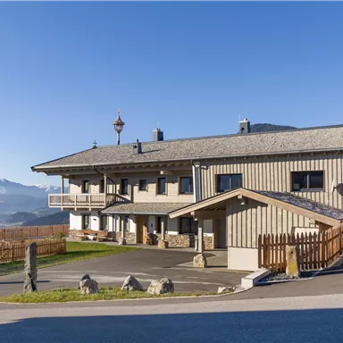 A modern building in the mountains with a clear blue sky.
Surrounded by a beautiful landscape and a wooden plank.