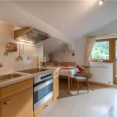 A modern kitchen corner with light wooden furniture and a large window. The room is friendly and inviting.