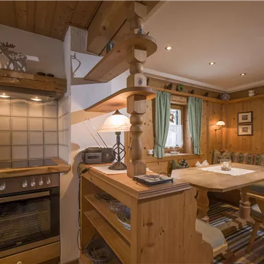 Eine gemütliche Küche mit Holzregalen und einem Essbereich. Die warmen Farben und die einladende Atmosphäre schaffen eine behagliche Stimmung.