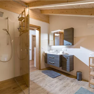 Ein modernes Badezimmer mit einer Glassch Dusche und einem Holzwaschbecken. Die Wände sind hell, und es gibt eine entspannte Atmosphäre.