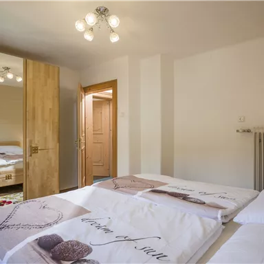 A modern bedroom with two beds and a large mirror. The room has a calm atmosphere and warm light.