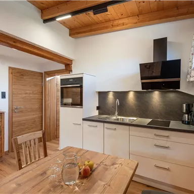 A modern kitchen with wooden elements and a cozy dining table group. The furniture is designed to be bright and friendly.