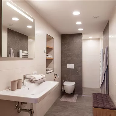 A modern bathroom with an elegant sink unit and a stylish shower. The walls are bright and the decor is simple and functional.