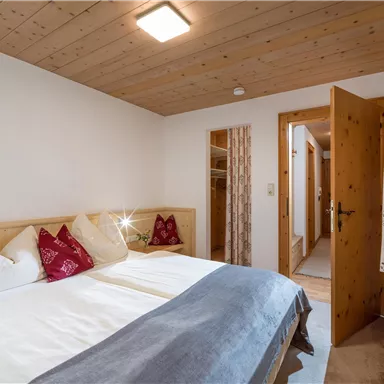 A cozy bedroom with two single beds and bright wood paneling. The interior design is simple and inviting.