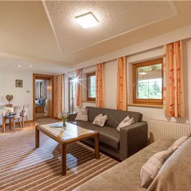 Cozy living room with a gray sofa and a wooden table. Large windows let in plenty of light, and the warm colors create an inviting atmosphere.