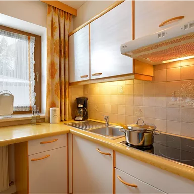 A modern kitchen with bright cabinets and a window. On the countertop, there is a pot and a coffee machine.