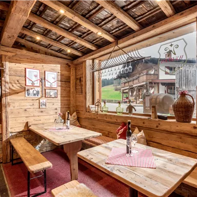 Ein gemütliches Restaurant mit Holzverkleidung und einer einladenden Atmosphäre. Durch das große Fenster sieht man die grüne Landschaft draußen.