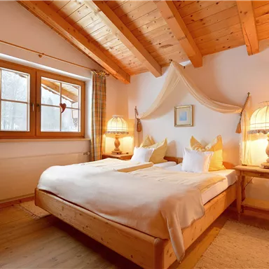 Ein gemütliches Schlafzimmer mit Holzdecke und zwei Betten. Es gibt große Fenster und warmes Licht von den Tischlampen.