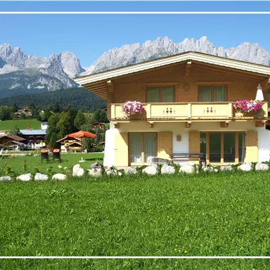 A beautiful, traditional house in a picturesque landscape. The mountains in the background and the green lawn create an idyllic atmosphere.