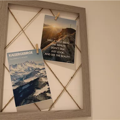 A picture frame with two posters. The left poster shows the Kaiser Mountains, the right encourages enjoying the beauty of nature.