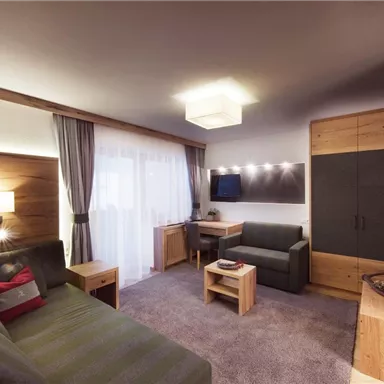 A modern living room with a cozy sofa, a table, and a television.  
Wood paneling and soft lighting create an inviting atmosphere.