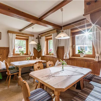 An inviting dining room with wooden paneling and cozy seating. The light streams through the windows, creating a warm atmosphere.