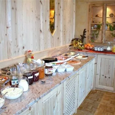 An inviting breakfast buffet with various cereals, jams, and fresh fruits. The wooden surfaces and warm colors create a cozy atmosphere.