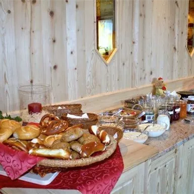 A lavish breakfast buffet with fresh rolls, pretzels, and various jams. The table is attractively decorated and invites you to enjoy.