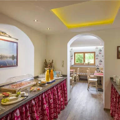 An inviting breakfast room with a buffet full of treats. In the background, you can see cozy seating areas and windows overlooking greenery.