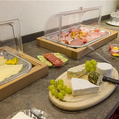 A lavish buffet with various types of cheese and cold cuts. In addition to grapes, fresh fruit and juices are also on display.