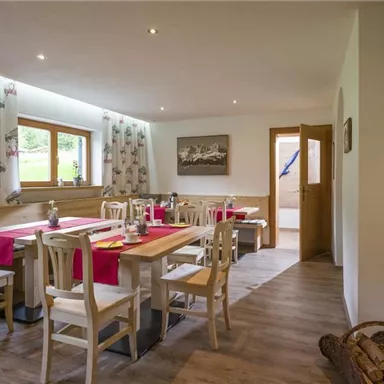 An inviting dining area with a wooden table and chairs. The windows let in plenty of light, and the cozy decor creates a warm atmosphere.
