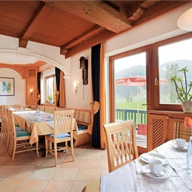 A cozy restaurant with wooden furniture and a view of the landscape through the windows. The table is beautifully set, and spring flowers decorate the room.