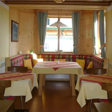 A cozy restaurant with wooden walls and an inviting table. The windows are bright and offer a view outside.
