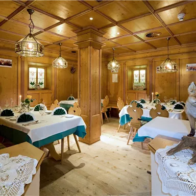 A rustic restaurant with wooden walls and lovingly decorated tables. A fox stands on a shelf, giving the room a special atmosphere.
