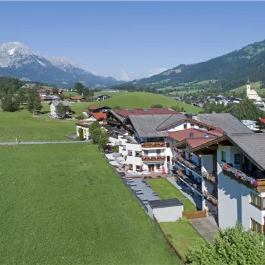 A picturesque landscape with green meadows and mountains in the background. The image shows a tranquil village with traditional buildings.