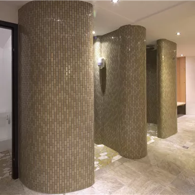 An elegant shower area with round tiled partitions. The floor is designed with light tiles and the lighting creates a pleasant atmosphere.