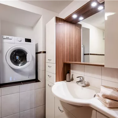 Ein modernes Badezimmer mit Dusche, WC und einer Waschmaschine zur kostenlosen Benützung.