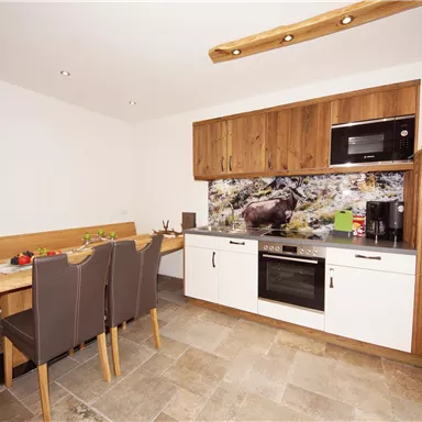 A modern kitchen with wooden cabinets and a cozy dining area. The walls are light, and the furnishings are modern and functional.