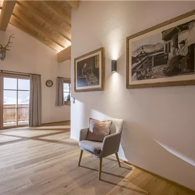 Ein modernes Zimmer mit Ausblick auf die Berge. Es gibt einen eleganten Sessel und zwei gerahmte Bilder an der Wand.