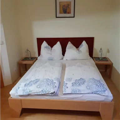 Ein gemütliches Schlafzimmer mit einem Doppelbett und zwei Nachttischen. Die Wände sind hell, und ein Bild hängt über dem Bett.