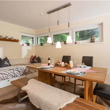 An inviting dining room with a large wooden table and comfortable chairs. The bright windows create a friendly atmosphere and plenty of natural light.