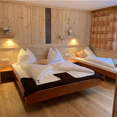 A cozy bedroom with wooden walls and two beds. The room is well-lit and tastefully furnished.