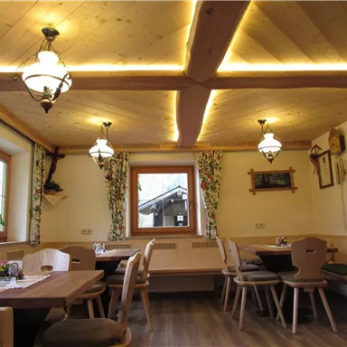 Ein gemütliches Restaurant mit Holzdecke und warmem Licht. Die Tische sind ordentlich gedeckt und es gibt Fenster mit Blick nach draußen.