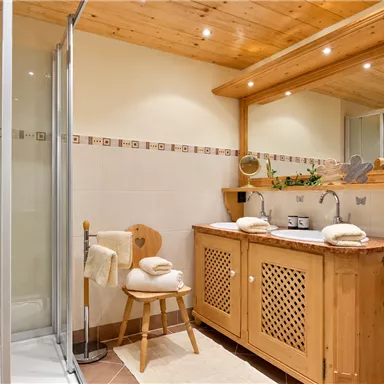 Ein modernes Badezimmer mit Holzdetails und einer Dusche. Der Waschbereich ist gut organisiert und bietet viel Platz.