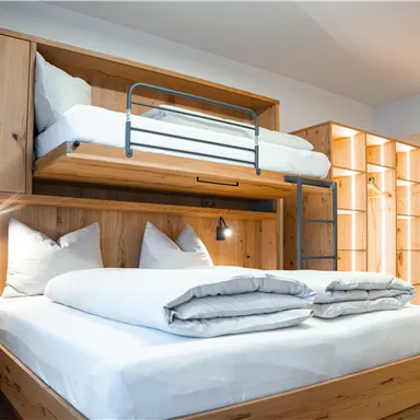 Ein modernes Schlafzimmer mit Holzregalen und zwei Betten. Der Raum ist hell und freundlich gestaltet.