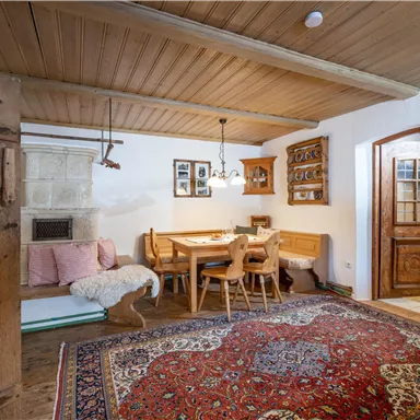 A cozy dining kitchen with wooden decor and a large rug. The room is bright and inviting, featuring a table and chairs made of wood.