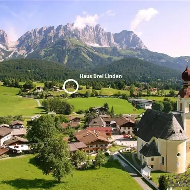 A picturesque alpine landscape with green meadows and majestic mountains. In the foreground stands a beautiful church and traditional houses.
