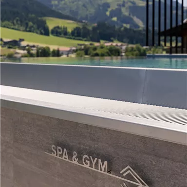 An elegant spa and fitness area with a view of gentle hills. The inscription "SPA & GYM" is clearly visible.