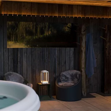 A relaxing wellness area with a jacuzzi and comfortable armchairs. The wood paneling and soft lighting create a cozy atmosphere.