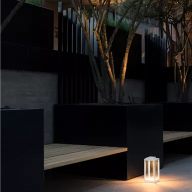 A modern ambiance with black benches and soft lighting. In the background, trees can be seen, adding a tranquil atmosphere to the space.
