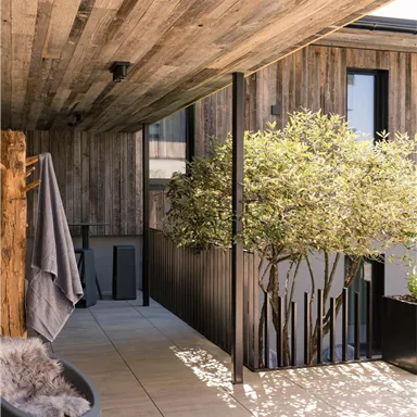 A modern terrace with wooden cladding and green plants. The space is bright and invitingly designed.