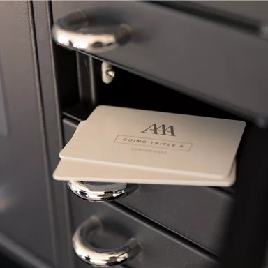 A close-up of a black cabinet with a white key card inserted. The card has a simple design and the slots are clearly visible.