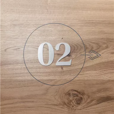 A wooden surface with the number 02 in a circle. Next to it is an arrow.