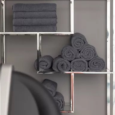 A modern shelf with several gray towels. The towels are neatly stacked and create an appealing arrangement.